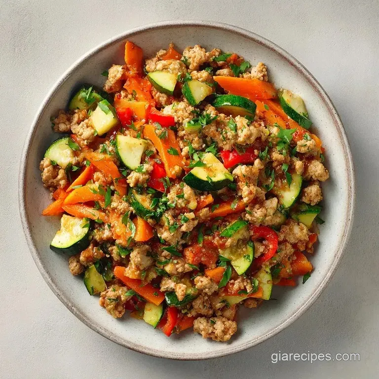 Sizzling cast iron pan of browned ground meat and colorful diced vegetables topped with chopped fresh parsley.