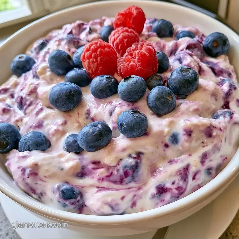 Velvety white oats layered with bursting purple berries in a glass jar, garnished with fresh green mint.