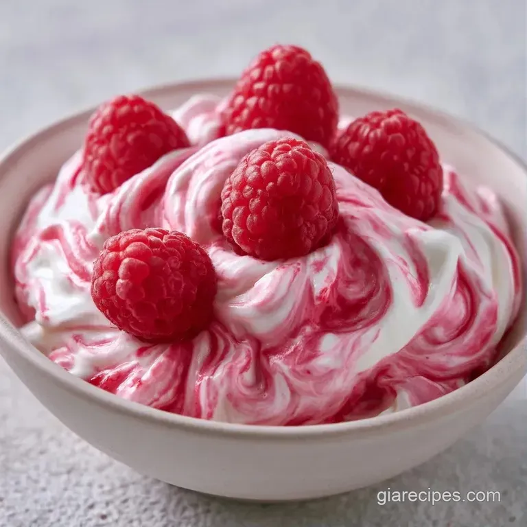 Pastel pink whipped cream served in crystal coupes, topped with a fresh raspberry and a delicate mint sprig leaf.