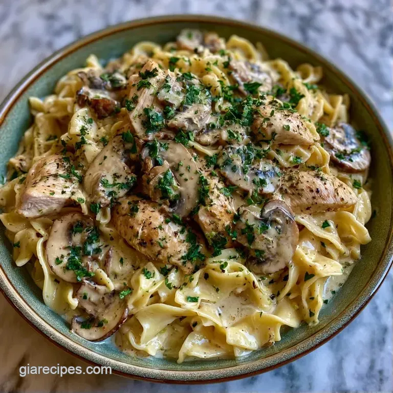 Golden-brown meat chunks in a velvety mushroom sauce atop a bed of pasta, garnished with fresh green parsley.