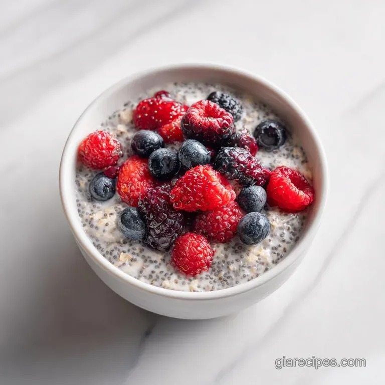 Clear glass jar showcasing layers of ivory-colored oats and vibrant red and blue berries on a rustic wooden table.