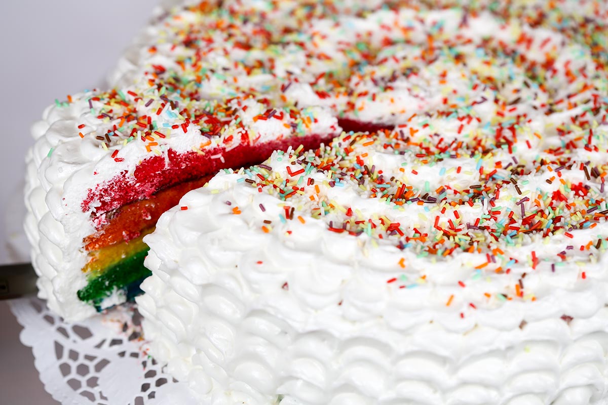 A slice of vibrant Funfetti Cake Lush Dessert with layers of cream, sprinkles, and whipped topping.