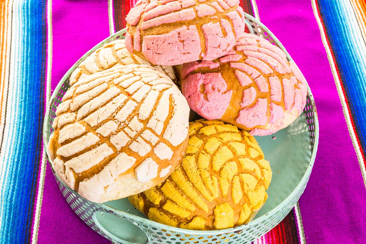 A variety of colorful Mexican bread, including Conchas and Pan de Muerto.