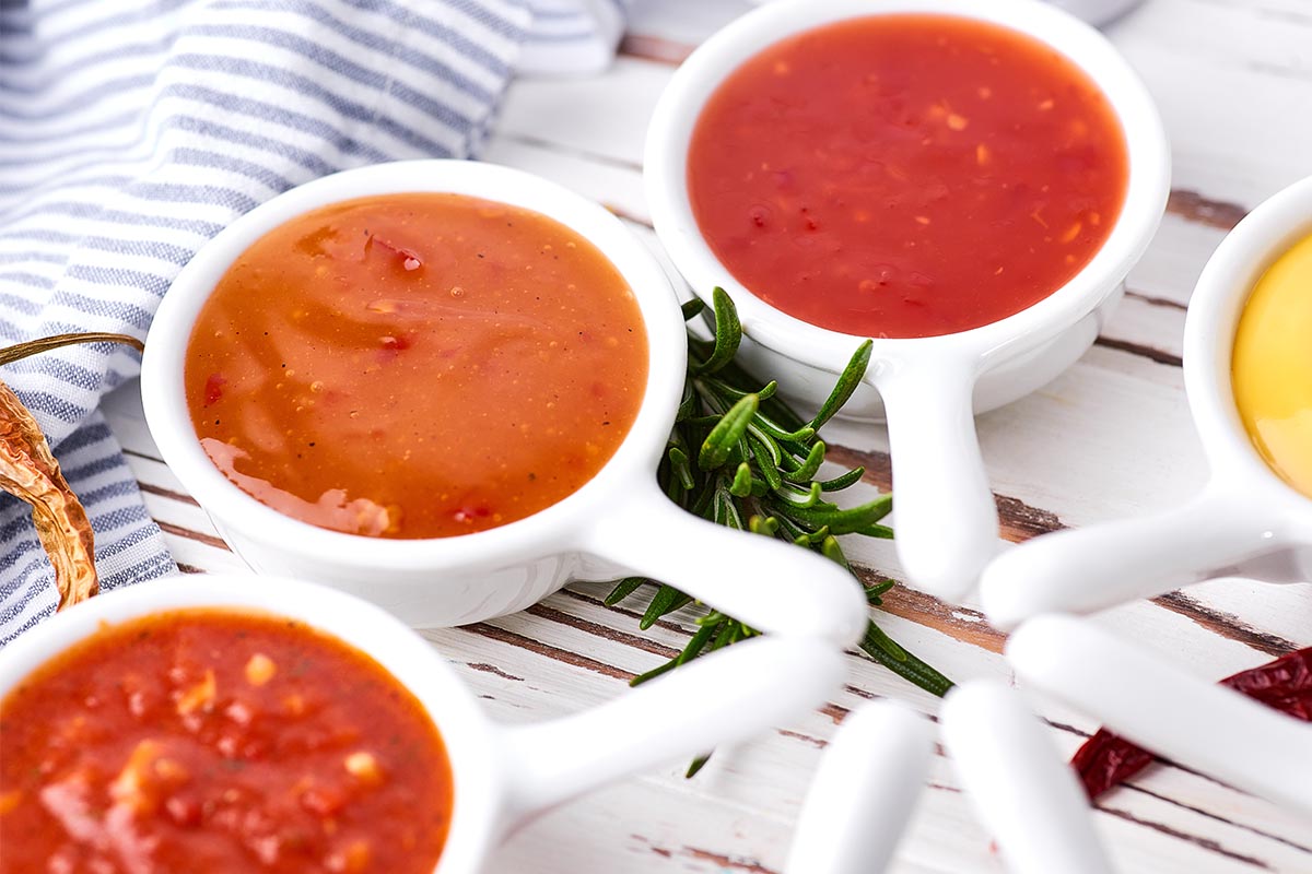 A bowl of creamy tomato bisque with fresh basil garnish, next to a bowl of traditional tomato soup with croutons.